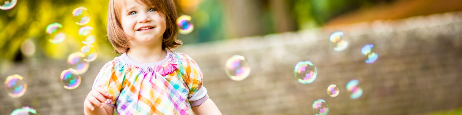 Close-up Of Smiling Little Standing Around Bubbles In Garden